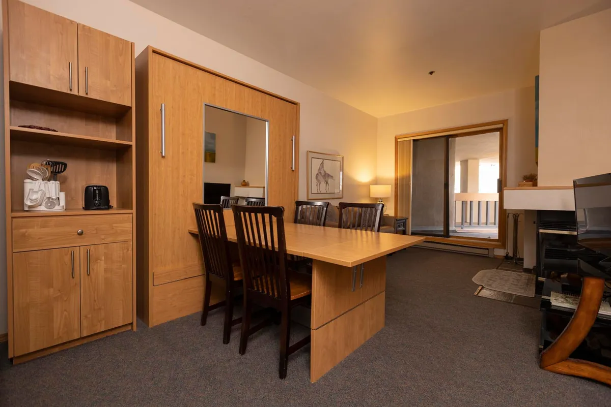 The dining nook features a sturdy table set near a sliding glass door, complemented by warm wooden cabinets and tasteful decorative artwork. The space exudes a cozy, welcoming atmosphere perfect for family meals, game nights, or casual gatherings with friends.
